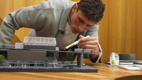 Young man painting an architectural model.